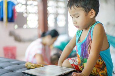 Küçük sevimli anaokulu çocuğu evde çizgi film izlerken tablet bilgisayar oynuyor.