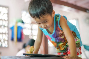 Küçük sevimli anaokulu çocuğu evde çizgi film izlerken tablet bilgisayar oynuyor.