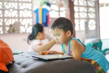 Küçük sevimli anaokulu çocuğu evde çizgi film izlerken tablet bilgisayar oynuyor.