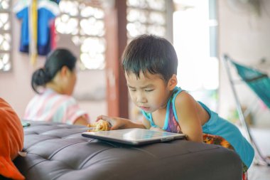 Küçük sevimli anaokulu çocuğu evde çizgi film izlerken tablet bilgisayar oynuyor.