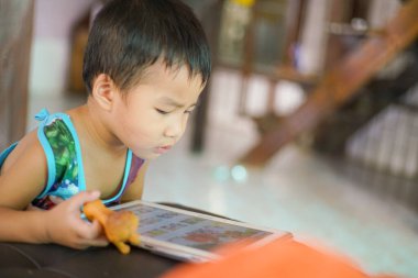 Küçük sevimli anaokulu çocuğu evde çizgi film izlerken tablet bilgisayar oynuyor.