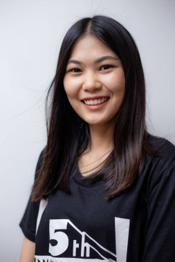 Güzel mutlu Asyalı kadın portresi beyaz arka planda siyah gömlek giyerek gülümsüyor.