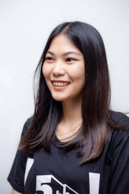 Güzel mutlu Asyalı kadın portresi beyaz arka planda siyah gömlek giyerek gülümsüyor.