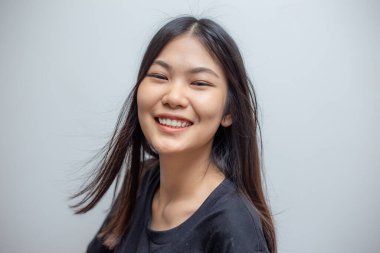 Gülümseyen, gülen Asyalı güzel, uzun saçlı bir kadının portresi.