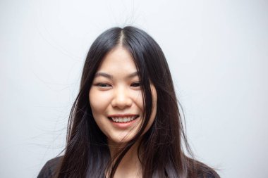 Gülümseyen, gülen Asyalı güzel, uzun saçlı bir kadının portresi.