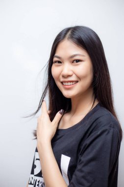 Güzel mutlu Asyalı kadın portresi beyaz arka planda siyah gömlek giyerek gülümsüyor.