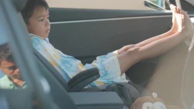 Asyalı kız çocuk araba koltuğunda oturuyor. 