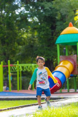 Anaokulu çocuğu çayırlarda koşuyor şehir bahçesinde oyun parkında mutlu çocuk.