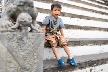 Küçük çocuk geleneksel Tayland kıyafeti giyer. Şafak vakti Budist tapınağı Wat Arun Bangkok Tayland 'a seyahat eder.