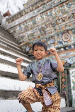 Küçük çocuk geleneksel Tayland kıyafeti giyer. Şafak vakti Budist tapınağı Wat Arun Bangkok Tayland 'a seyahat eder.