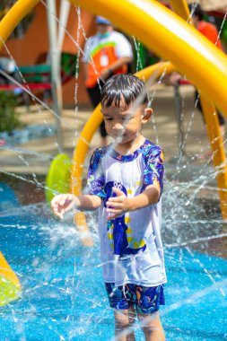 Küçük Asyalı anaokulu çocuğu yaz etkinliklerindeki açık su parkında eğleniyor.