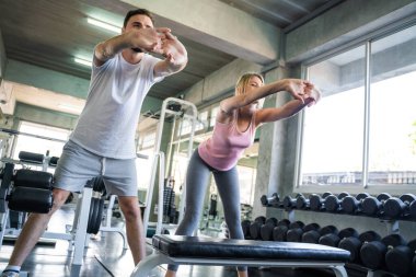 Couple stretch body before exercise in sport gym together private trainer healthy lifestyle