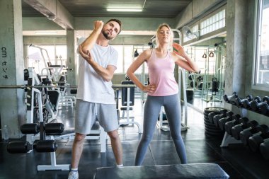 Couple stretch body before exercise in sport gym together private trainer healthy lifestyle