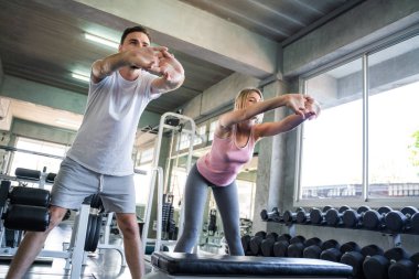 Couple stretch body before exercise in sport gym together private trainer healthy lifestyle