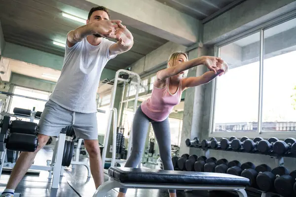 Couple stretch body before exercise in sport gym together private trainer healthy lifestyle