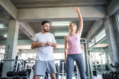 Couple stretch body before exercise in sport gym together private trainer healthy lifestyle