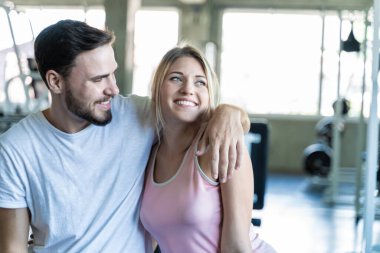 Spor adamı ve kadın spor salonunda oturup egzersizden sonra rahatlıyorlar.