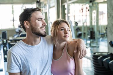 Spor adamı ve kadın spor salonunda oturup egzersizden sonra rahatlıyorlar.