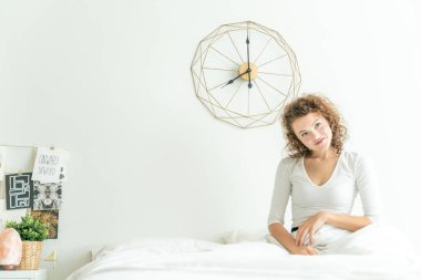 Güzel bir kadın sabah beyaz yatakta uyanır.