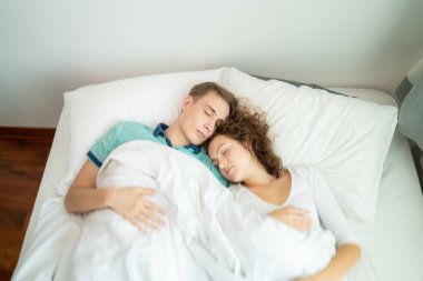 Beyaz yatakta uyuyan mutlu beyaz bir çift. Aşk romantizmi. Sevgililer Günü kavramı.