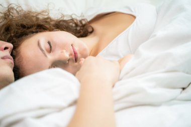 Beyaz yatakta uyuyan mutlu beyaz bir çift. Aşk romantizmi. Sevgililer Günü kavramı.