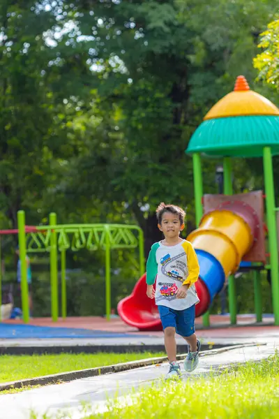 Anaokulu çocuğu çayırlarda koşuyor şehir bahçesinde oyun parkında mutlu çocuk.