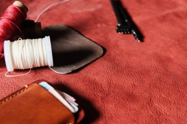 Hakiki kırmızı kahverengi deri kart yuvası deri arka planda el sanatları aracı ile çalışıyor