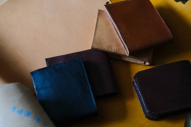 Hakiki çift katlı cüzdan deri. Deri arka planda el yapımı cüzdan ustalığı ile çalışıyor.