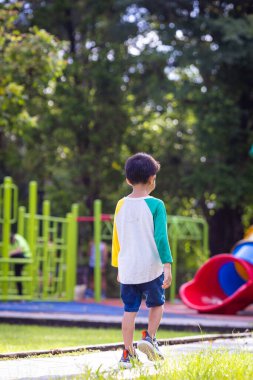 Anaokulu çocuğu şehir parkında çimlerde koşuyor.