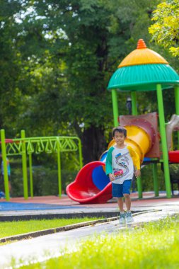 Anaokulu çocuğu şehir parkında çimlerde koşuyor.