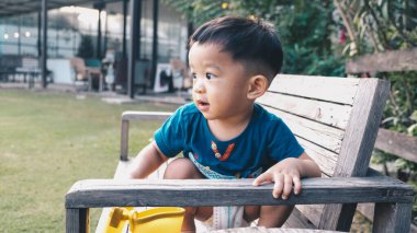 Mutlu çocuk doğa parkında açık havada tahta oyun alanında oynuyor.