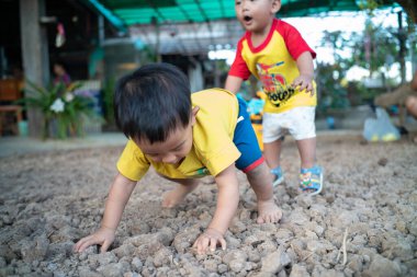 Sevimli küçük çocuk dışarıda toprağın üstünde oynuyor ve sürünüyor.