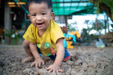 Sevimli küçük çocuk dışarıda toprağın üstünde oynuyor ve sürünüyor.