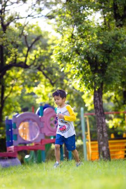 Anaokulu çocuğu şehir parkında koşuyor, mutlu çocuk kendini özgür hissediyor.