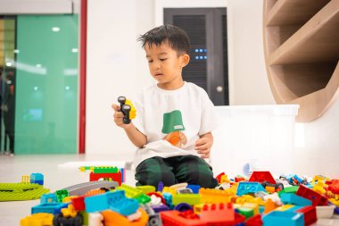 Anaokulundaki Asyalı çocuk okul eğitim odasında renkli oyuncaklar inşa etmekten zevk alıyor. 