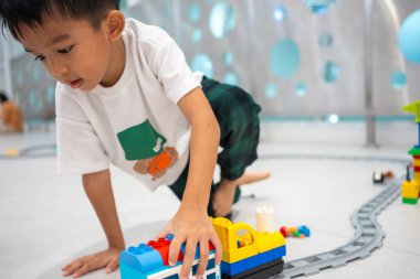 Anaokulundaki Asyalı çocuk okul eğitim odasında renkli oyuncaklar inşa etmekten zevk alıyor. 