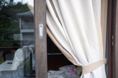 Otel odasındaki kanepeli modern perde toprak tonunda ahşap süslemeli tropikal otel tatil köyü.