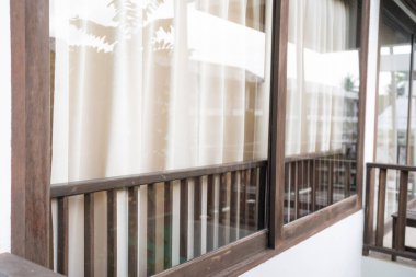 Otel odasındaki kanepeli modern perde toprak tonunda ahşap süslemeli tropikal otel tatil köyü.