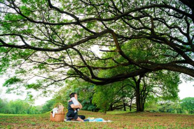 Asyalı anne, parkta piknikte bebekle oynuyor. Açık hava eğlencesi konsepti. 