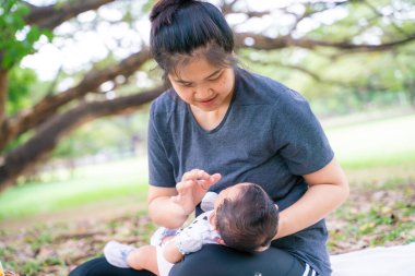 Asyalı anne, parkta piknikte bebekle oynuyor. Açık hava eğlencesi konsepti. 