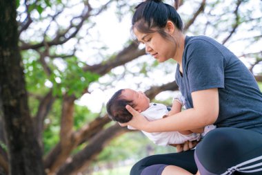 Asyalı anne, parkta piknikte bebekle oynuyor. Açık hava eğlencesi konsepti. 