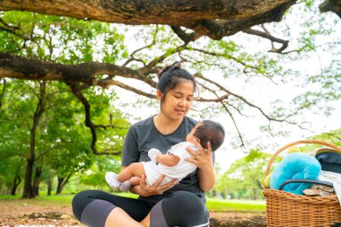 Asyalı anne, parkta piknikte bebekle oynuyor. Açık hava eğlencesi konsepti. 