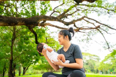 Asyalı anne, parkta piknikte bebekle oynuyor. Açık hava eğlencesi konsepti. 