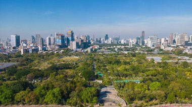 Bangkok Tayland şehir merkezindeki Benchakitti halk parkında tropik yeşil ağaç parkı olan modern ofis binası.