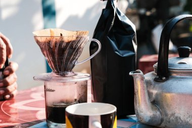 İnsanlar sabahları evdeki açık hava masasında filtrelenmiş kahve damlalarıyla konuşuyorlar.