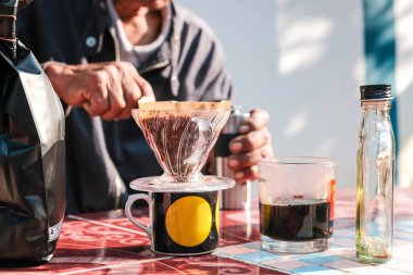 İnsanlar sabahları evdeki açık hava masasında filtrelenmiş kahve damlalarıyla konuşuyorlar.