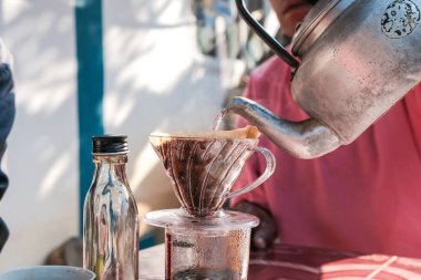 İnsanlar sabahları evdeki açık hava masasında filtrelenmiş kahve damlalarıyla konuşuyorlar.