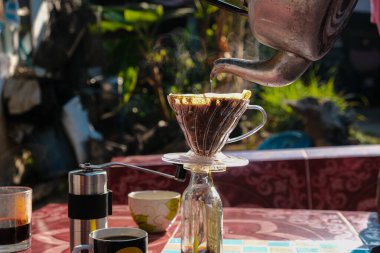 İnsanlar sabahları evdeki açık hava masasında filtrelenmiş kahve damlalarıyla konuşuyorlar.