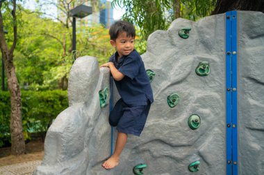 Küçük Asyalı çocuk tepenin üstüne tırmanmayı seviyor açık şehir parkı spor çocuğu.