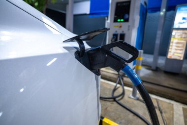 EV şarj kolu geceleri elektrikli araba istasyonuna bağlı, alternatif ve sürdürülebilir enerji ile EV araba aküsünü şarj ediyor
